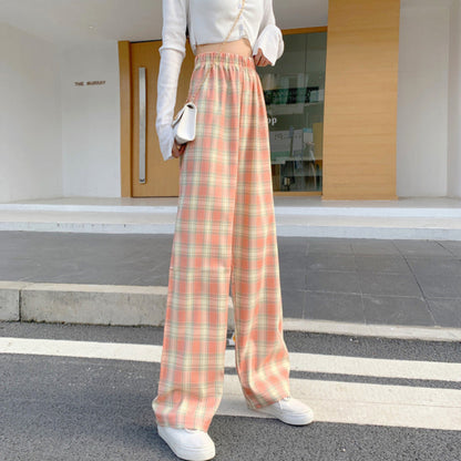 Pantaloni a quadri larghi donna, vita alta, colori pastello, abbinati a top bianco corto e sneakers bianche, moda casual urbana.