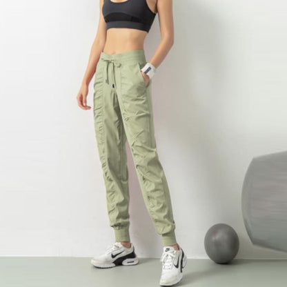 Donna in abbigliamento sportivo: top nero, pantaloni cargo verdi, scarpe da ginnastica bianche. Fitness, moda sportiva, allenamento.