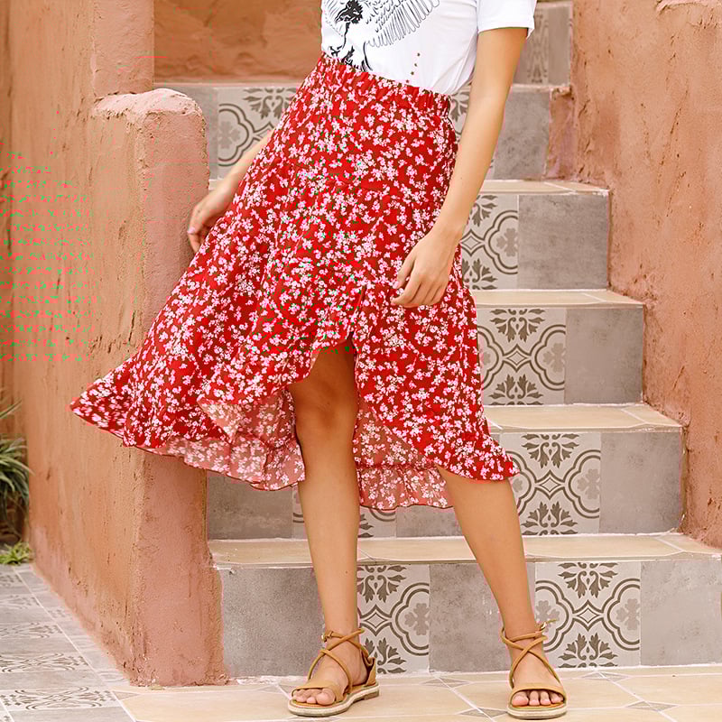 Gonna rossa a fiori bianchi, stile boho, indossata su scale decorate. Moda estiva femminile, look casual chic.