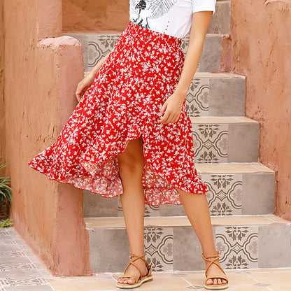 Gonna rossa a fiori bianchi, stile boho, indossata su scale decorate. Moda estiva femminile, look casual chic.