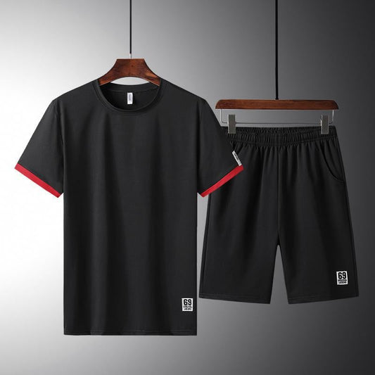 Completo sportivo nero da uomo, maglietta e pantaloncini, dettagli rossi, tessuto traspirante, ideale per allenamento e fitness.