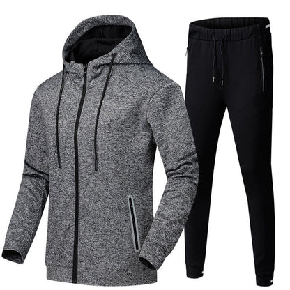 Tuta sportiva uomo, giacca grigia con cappuccio e pantaloni neri, abbigliamento fitness, moda casual, tessuto traspirante, stile moderno.