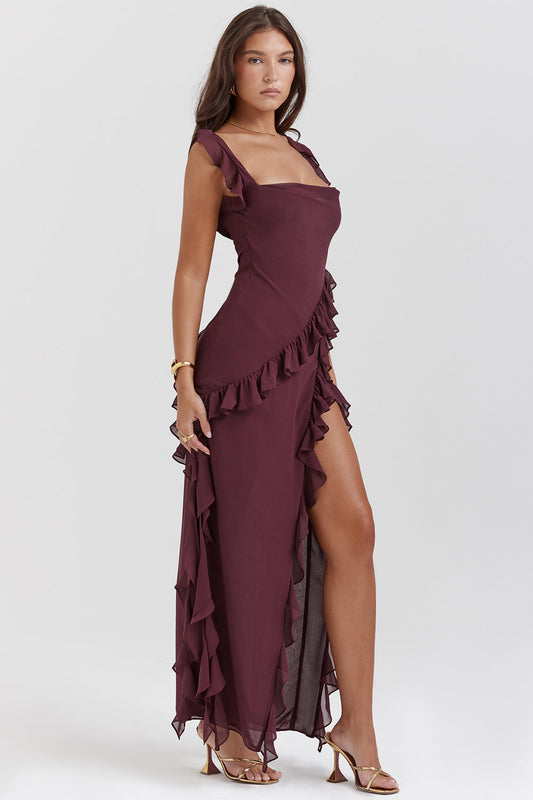 Donna in abito lungo bordeaux con volant, spacco laterale e sandali dorati. Moda elegante, abbigliamento da sera, tendenze 2023.