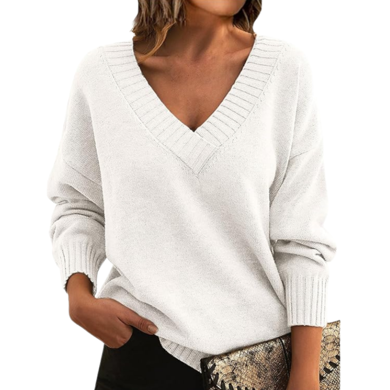Donna con maglione bianco a V, maniche lunghe, tiene una pochette con stampa serpente. Moda autunnale, abbigliamento casual elegante.
