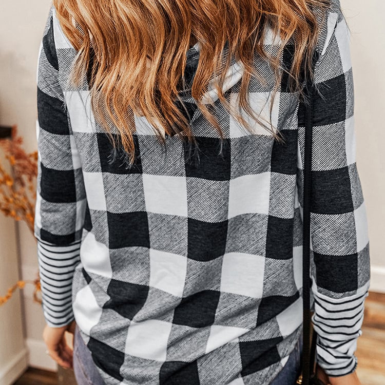 Donna con camicia a quadri bianco e nero, capelli castani ondulati, in un ambiente interno. Moda autunnale, stile casual, tendenze abbigliamento.