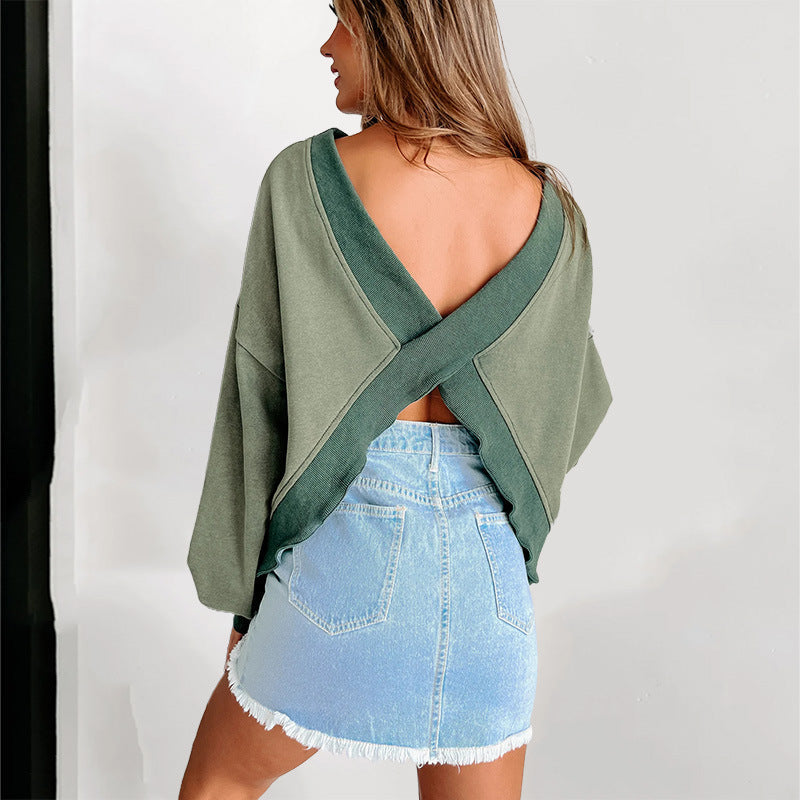 Donna di spalle con maglione verde incrociato e gonna di jeans corta. Moda casual, abbigliamento femminile trendy, stile autunnale.