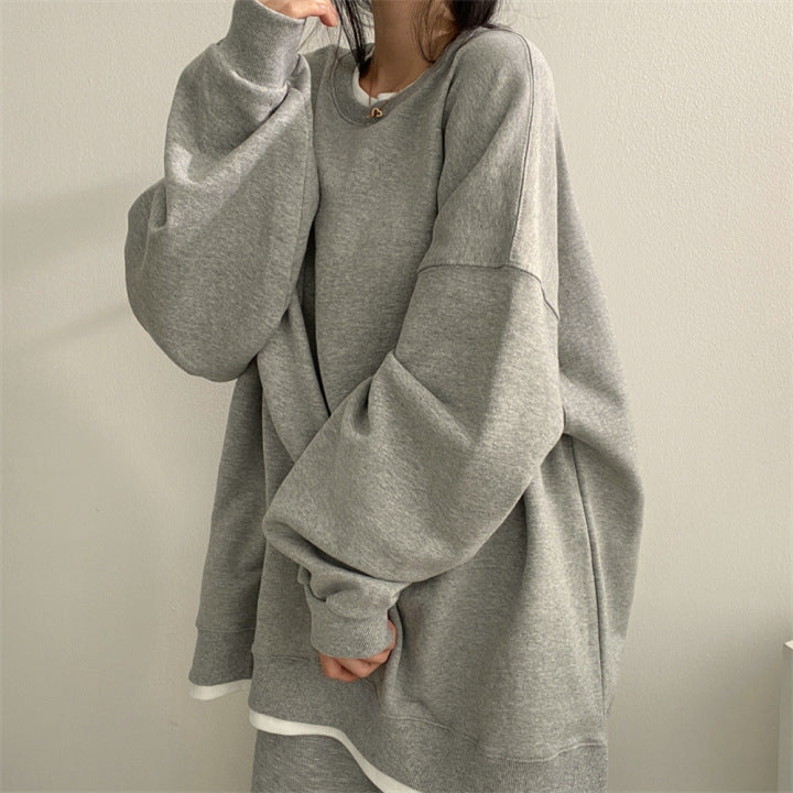 Donna con felpa oversize grigia, moda casual, abbigliamento comodo, stile minimalista, tendenza streetwear, sfondo neutro.