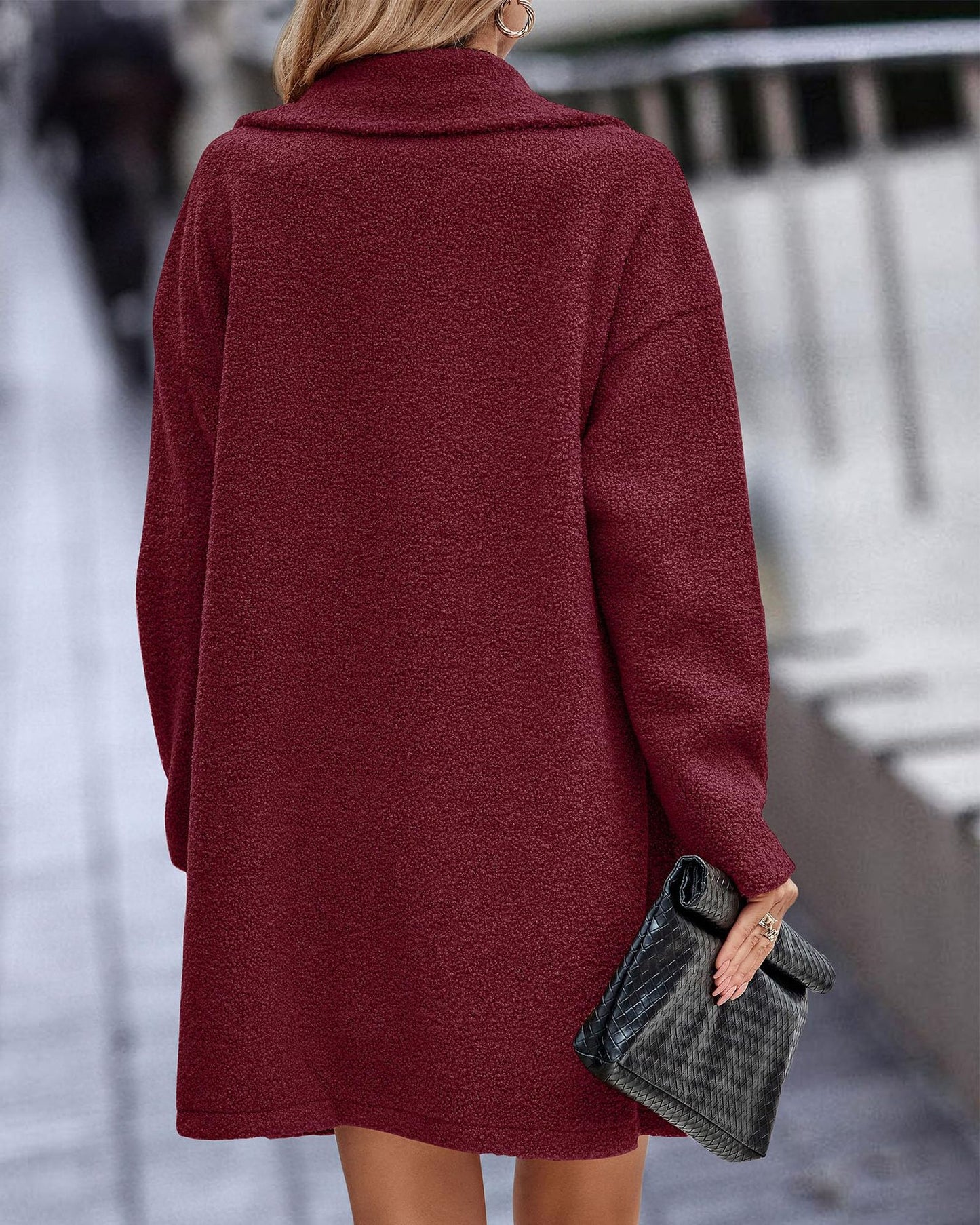 Donna con cappotto rosso borgogna, tessuto morbido, tiene una borsa nera. Moda autunnale, abbigliamento elegante per il freddo.