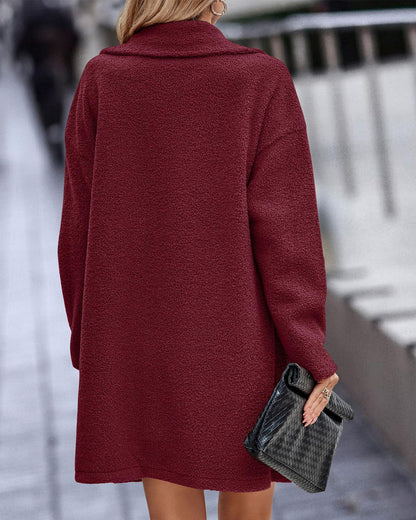 Donna con cappotto rosso borgogna, tessuto morbido, tiene una borsa nera. Moda autunnale, abbigliamento elegante per il freddo.