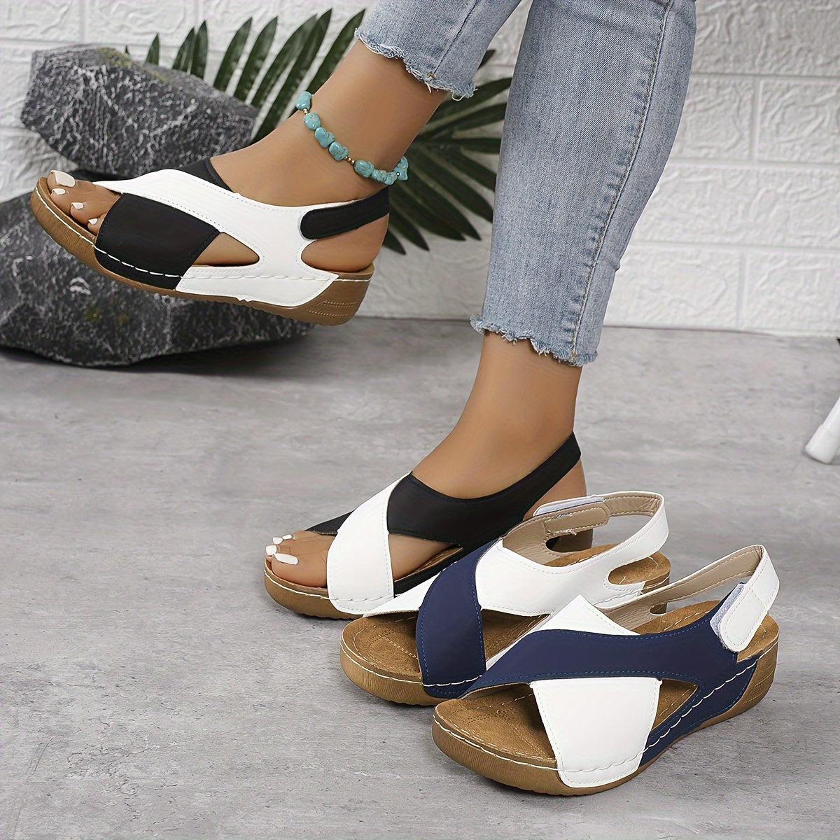 Sandali estivi donna con zeppa, design bicolore nero e bianco, suola in sughero, indossati con jeans. Scarpe comode e alla moda per l'estate.