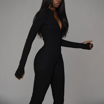 Donna in tuta nera aderente su sfondo grigio, moda elegante, abbigliamento femminile moderno, stile minimalista, tendenza autunno inverno.