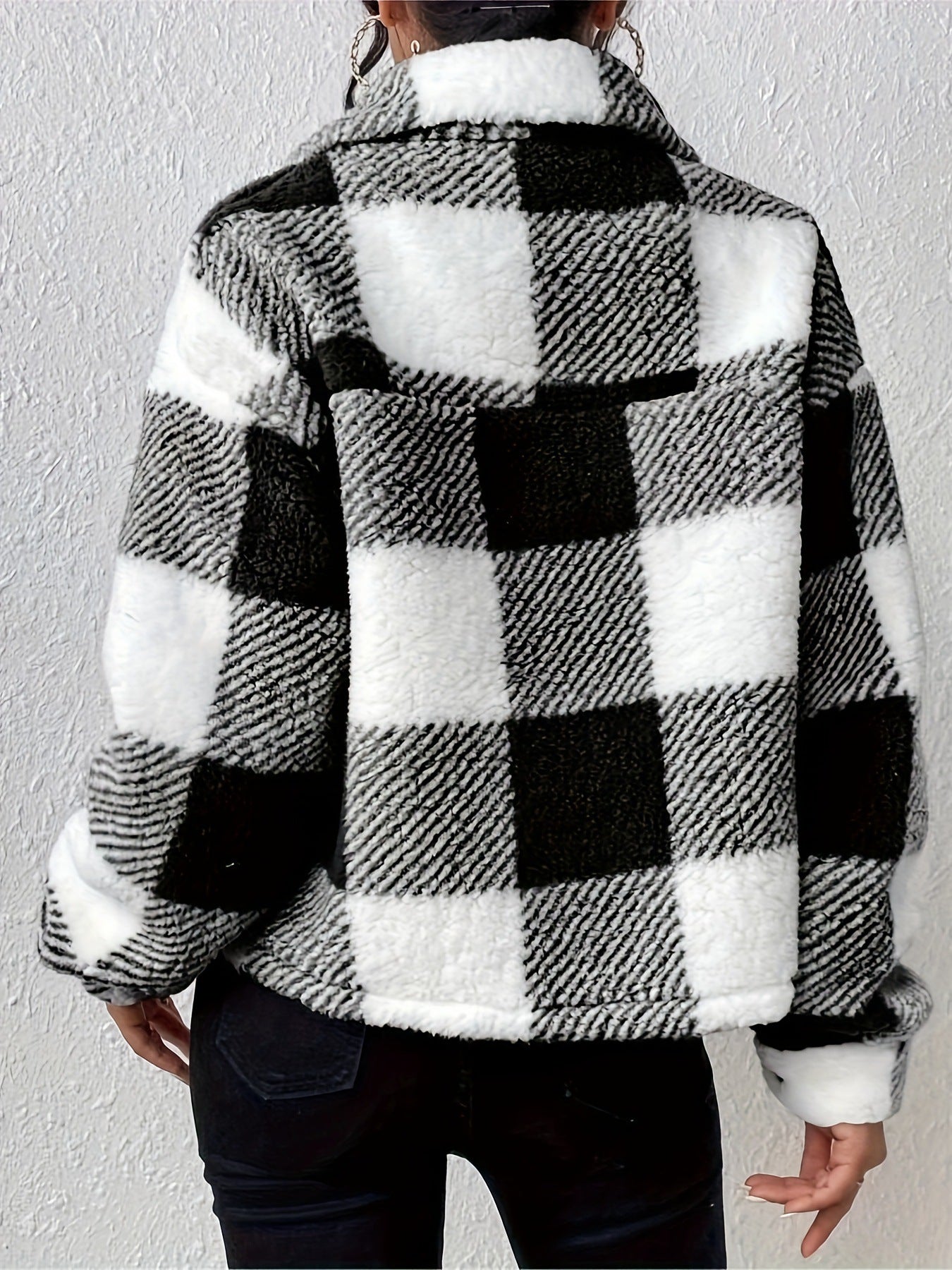Giacca a quadri bianco e nero in pile, stile casual, indossata da una persona di spalle. Tessuto morbido e caldo, ideale per l'inverno.