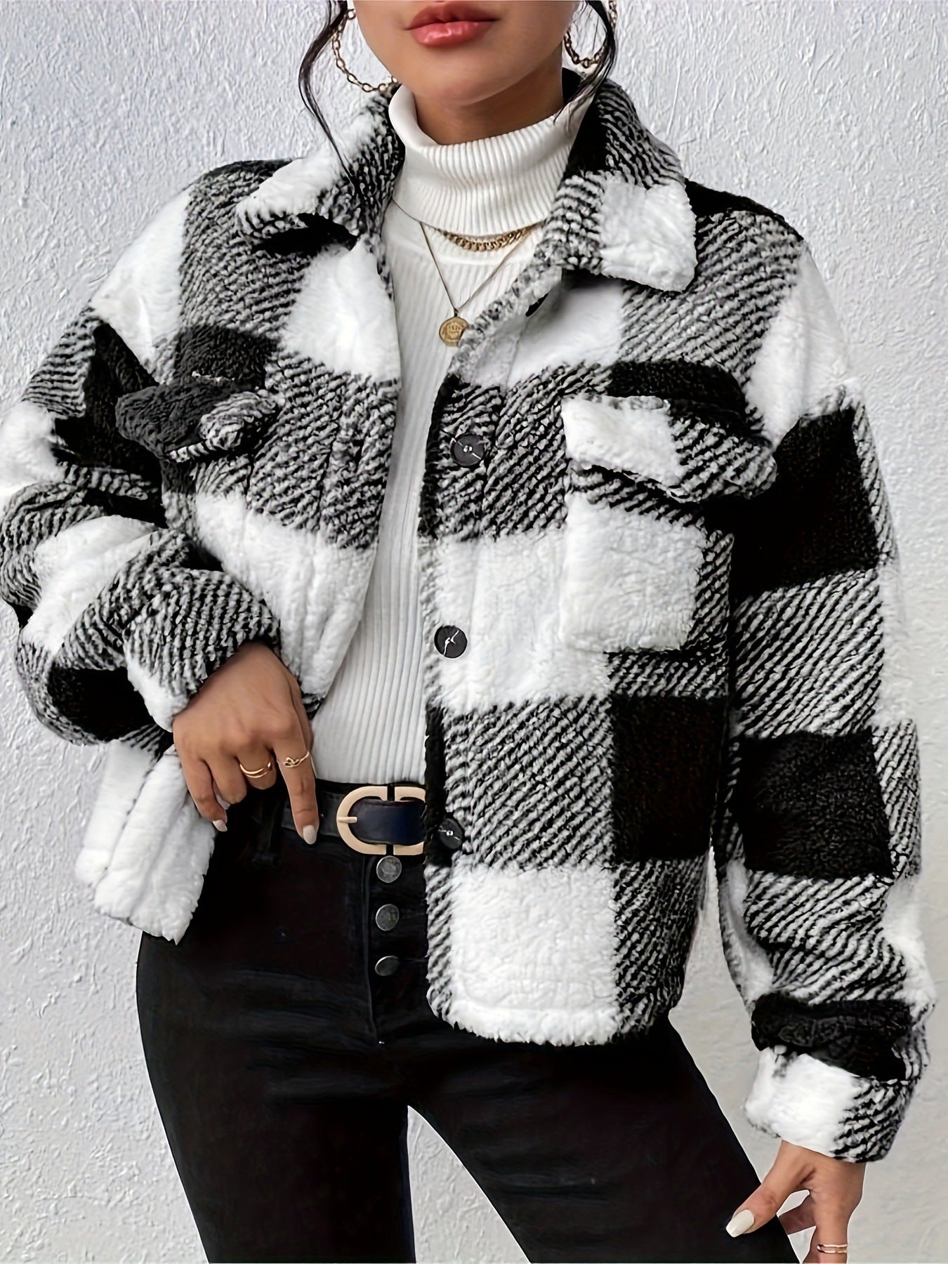 Giacca a quadri bianco e nero in pile, indossata su dolcevita bianco. Moda autunno inverno, stile casual chic, dettagli con bottoni e cintura nera.