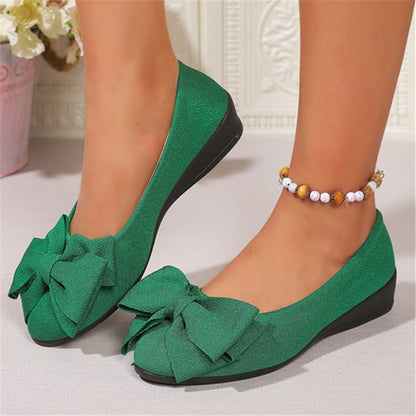 Scarpe ballerine verdi con fiocco, indossate su piedi femminili, abbinate a cavigliera con perline. Design elegante e moderno per moda donna.