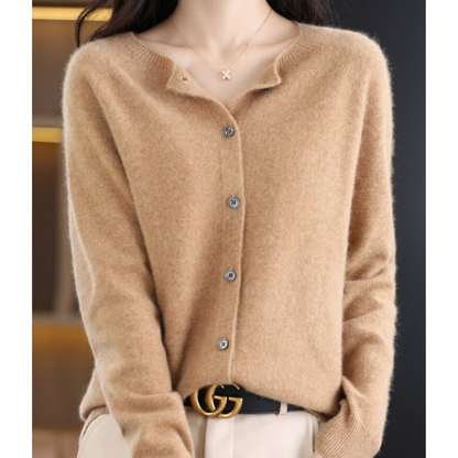 Maglione beige in cashmere con bottoni, indossato da una donna. Accessori: collana con ciondolo a X e cintura nera con fibbia dorata.