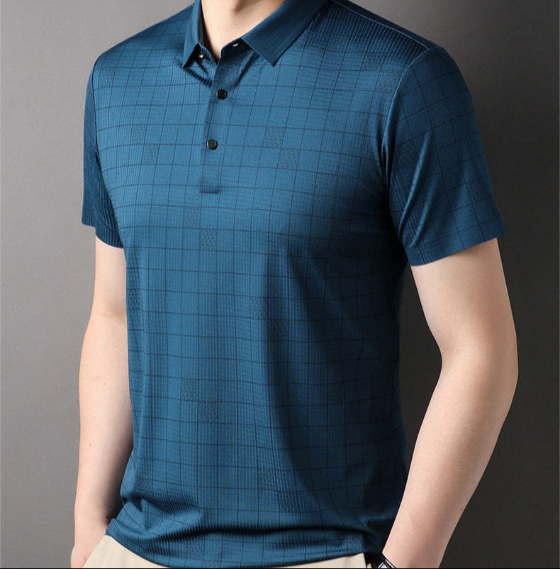 Maglietta polo blu a quadri, maniche corte, indossata da uomo su sfondo grigio. Stile casual elegante, moda maschile contemporanea.