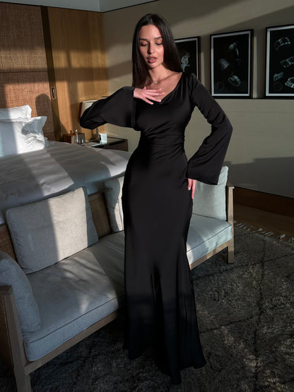 Donna in abito nero elegante in una camera da letto moderna, illuminata dalla luce naturale. Arredamento di lusso, atmosfera sofisticata.