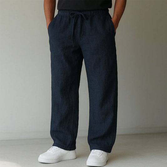 Pantaloni larghi blu scuro in lino, indossati con scarpe da ginnastica bianche. Stile casual, moda uomo, abbigliamento estivo.