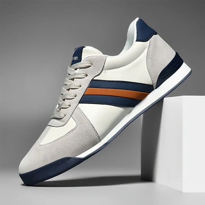 Scarpa da ginnastica moderna bianca e blu con dettagli arancioni, suola in gomma, design elegante e sportivo, perfetta per moda casual e comfort.