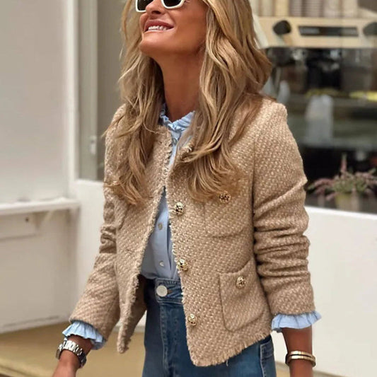 Donna sorridente con occhiali da sole bianchi, indossa giacca beige in tweed e jeans. Moda autunnale, stile casual chic, tendenze abbigliamento femminile.