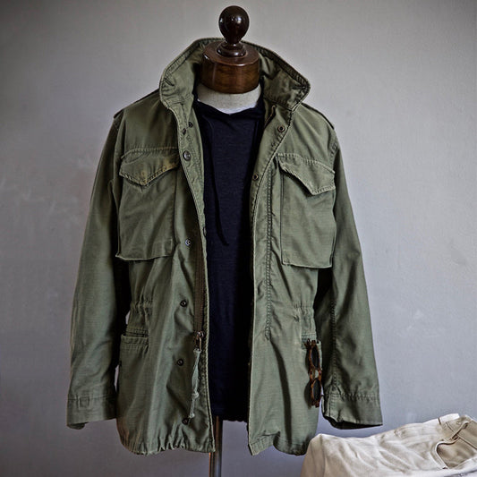 Giacca militare verde oliva su manichino, stile casual, tasche multiple, moda uomo autunno, abbigliamento outdoor resistente e versatile.