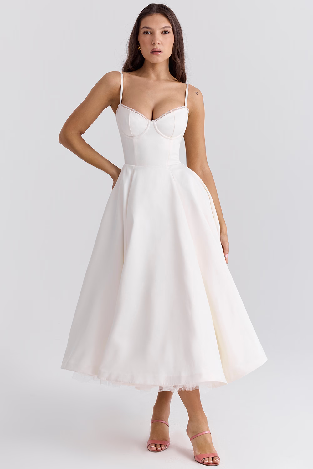 Donna in abito da sposa bianco elegante, lunghezza midi, con spalline sottili e scollo a cuore. Perfetto per matrimoni moderni e cerimonie estive.
