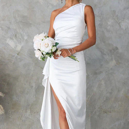 Abito da sposa bianco monospalla con spacco laterale, bouquet di rose bianche, sfondo grigio. Elegante e moderno, perfetto per matrimoni.