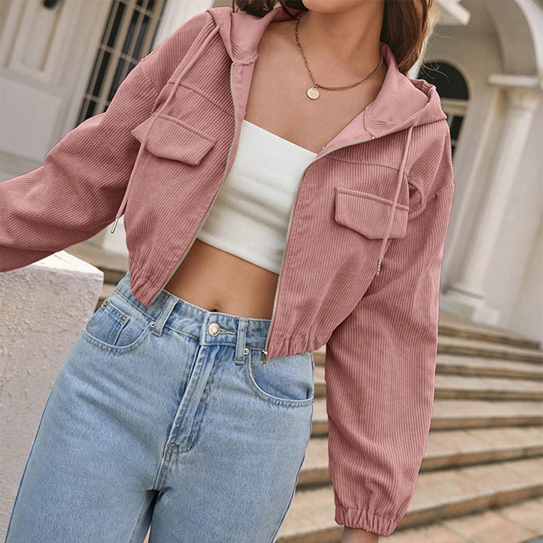 Donna con giacca rosa a coste, top bianco e jeans a vita alta. Moda casual femminile, abbigliamento trendy, stile urbano.