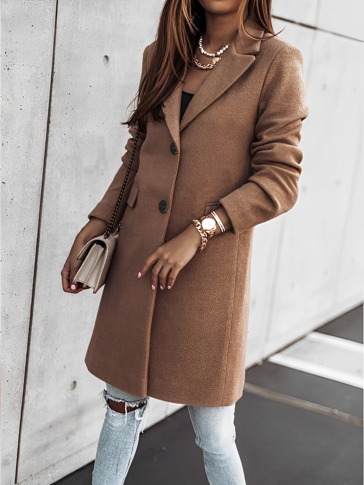 Donna con cappotto marrone elegante, jeans strappati, borsa beige e orologio dorato. Moda autunnale, stile casual chic, tendenze abbigliamento femminile.