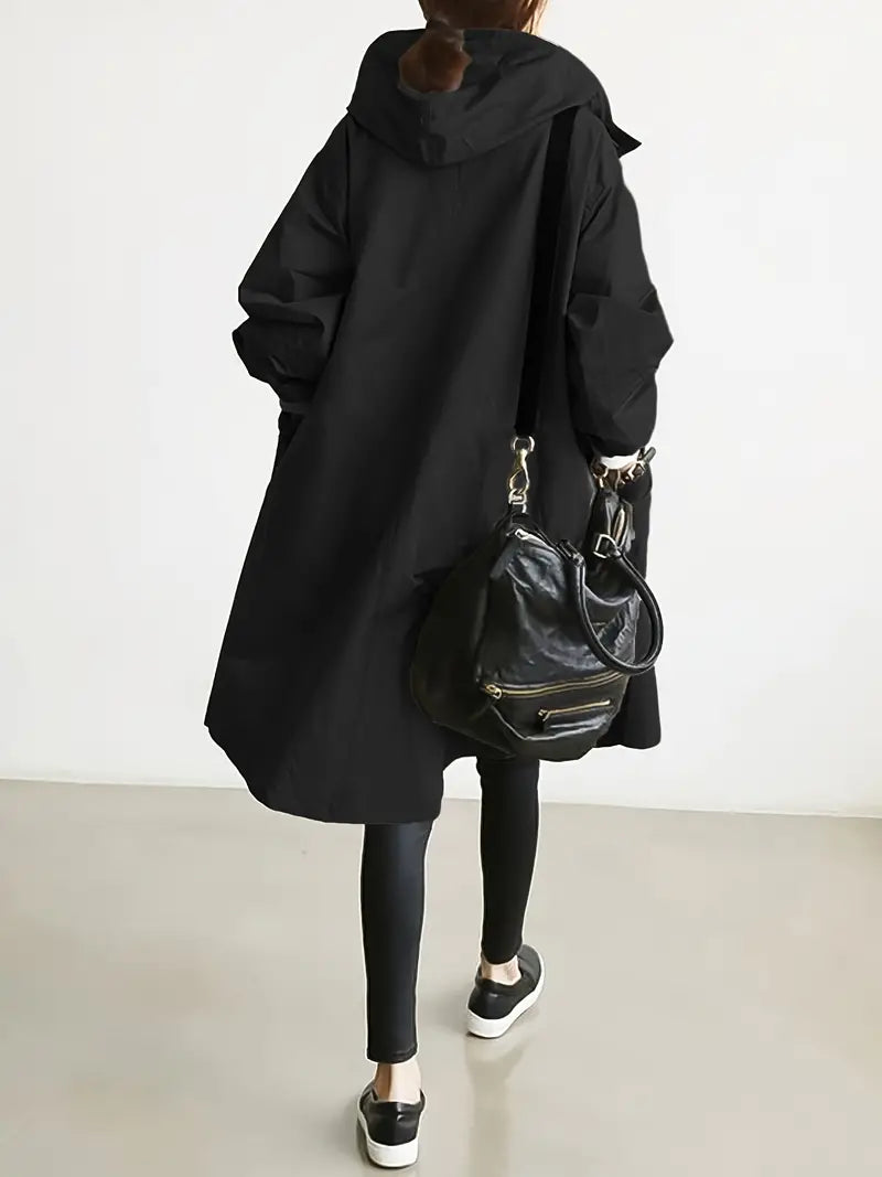 Donna di spalle con cappotto nero oversize, leggings e borsa a tracolla in pelle. Moda casual autunnale, stile urbano minimalista.