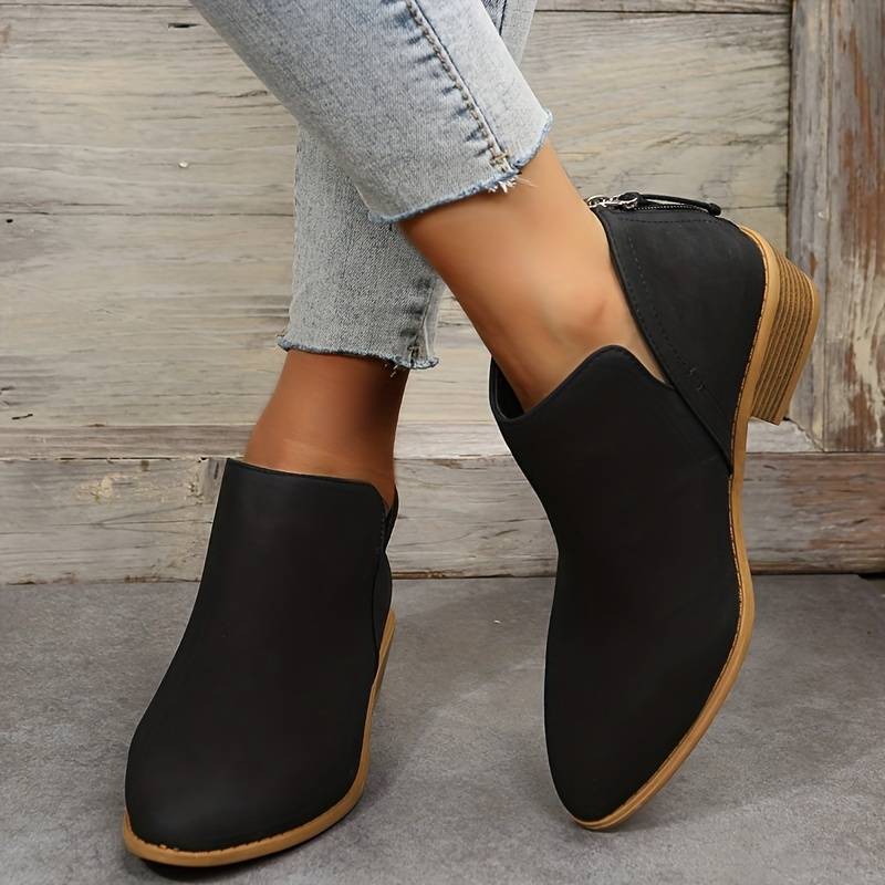 Stivaletti neri donna con tacco basso, design moderno, abbinati a jeans chiari. Scarpe eleganti e comode per look casual e alla moda.