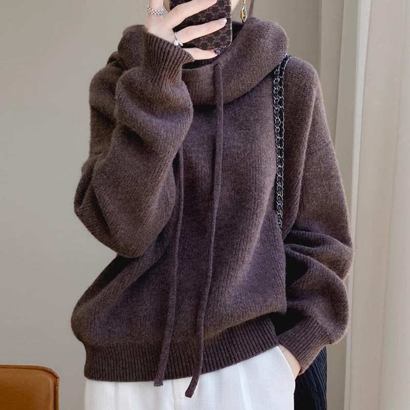 Donna con maglione marrone oversize in lana, cappuccio e lacci, borsa a tracolla nera, moda autunno inverno, stile casual chic.