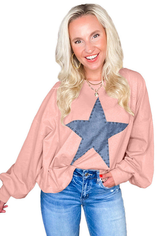 Donna sorridente con maglia rosa a stella blu, jeans casual. Moda femminile, abbigliamento autunnale, stile casual chic.