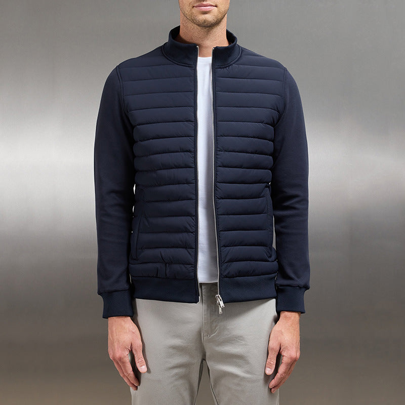 Giacca uomo blu scuro imbottita, stile casual, con zip frontale, indossata su maglietta bianca e pantaloni grigi. Moda maschile autunno.