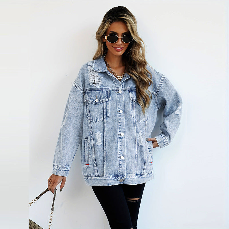 Donna con giacca di jeans oversize strappata, occhiali da sole e capelli ondulati. Moda casual, stile urbano, tendenza denim 2023.