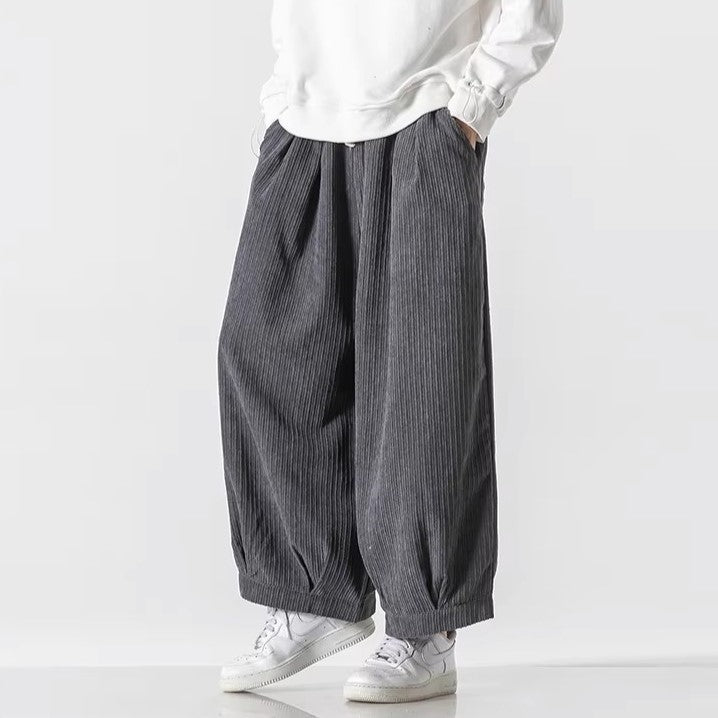 Pantaloni larghi a righe grigie, stile casual, indossati con felpa bianca e sneakers bianche. Moda uomo, abbigliamento comodo e moderno.