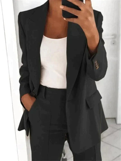 Donna in abito elegante nero, giacca e pantaloni, con top bianco. Moda business casual, outfit professionale, stile moderno.