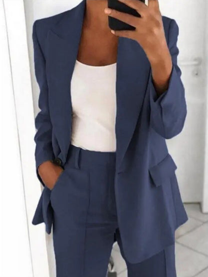 Donna in abito elegante blu, giacca e pantaloni coordinati, indossa top bianco. Moda business casual, outfit professionale per ufficio.