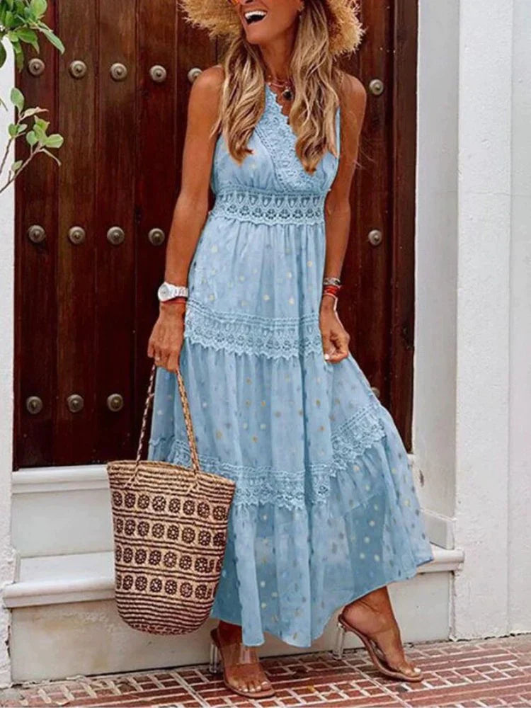 Donna con abito lungo azzurro in pizzo, cappello di paglia e borsa intrecciata, davanti a una porta in legno. Moda estiva elegante e casual.