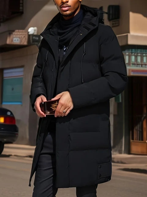 Uomo con cappotto nero invernale, elegante e moderno, tiene uno smartphone. Moda urbana, abbigliamento caldo, strada cittadina.