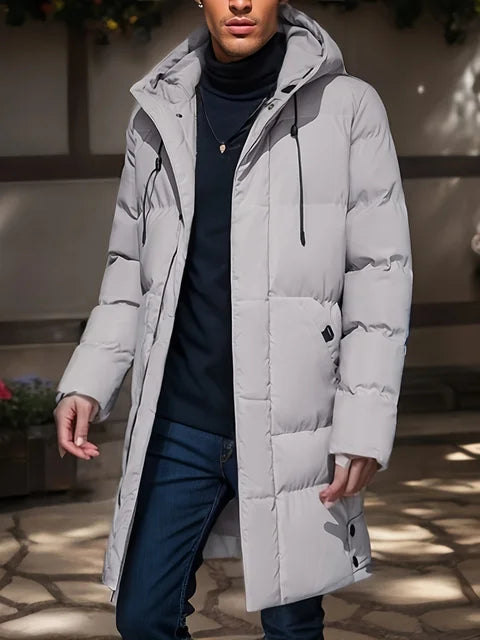 Giacca invernale uomo, piumino grigio chiaro con cappuccio, design moderno, indossato su maglione nero e jeans. Moda maschile autunno inverno.
