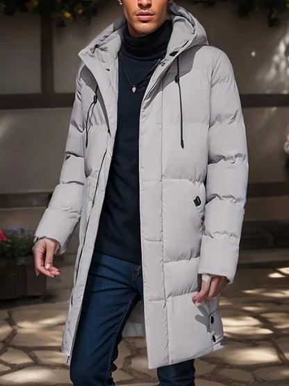 Giacca invernale uomo, piumino grigio chiaro con cappuccio, design moderno, indossato su maglione nero e jeans. Moda maschile autunno inverno.
