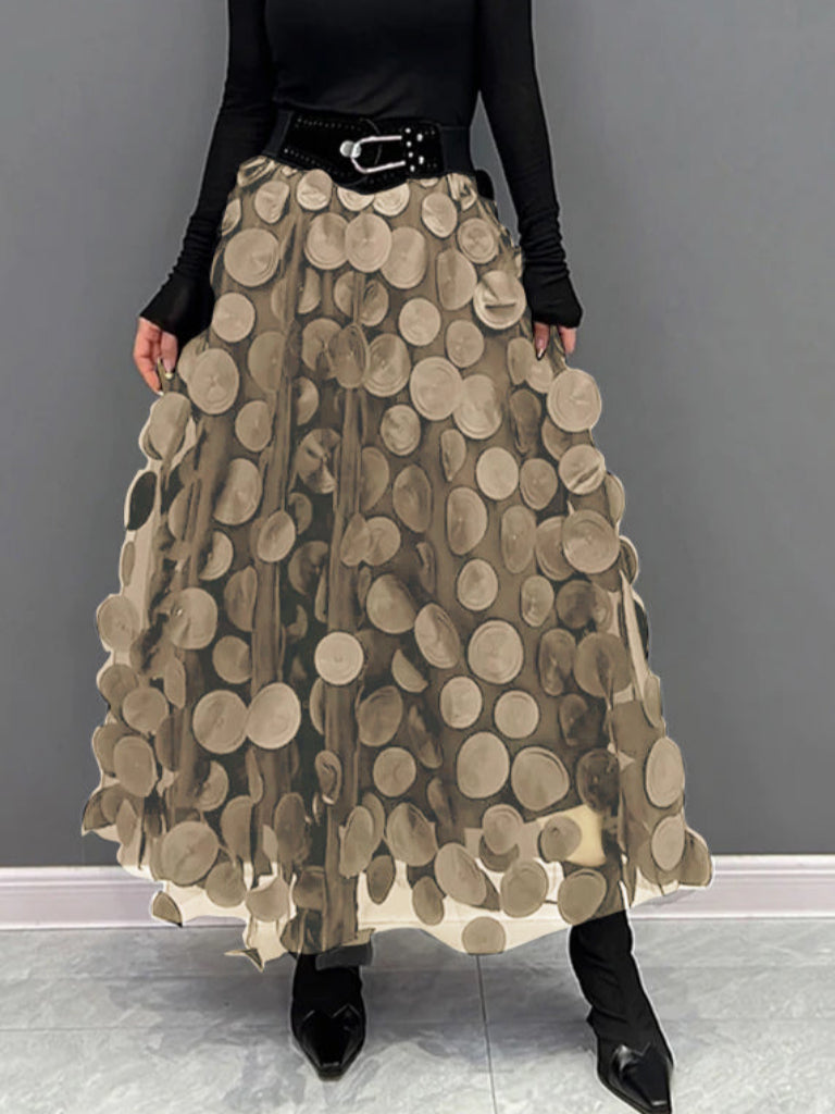 Gonna lunga beige con cerchi decorativi, cintura nera, indossata con top nero a maniche lunghe. Moda femminile elegante e moderna.