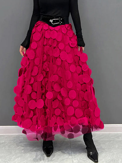 Gonna lunga rosa con cerchi decorativi, indossata con cintura nera e stivali a punta. Moda femminile elegante, abbigliamento trendy.