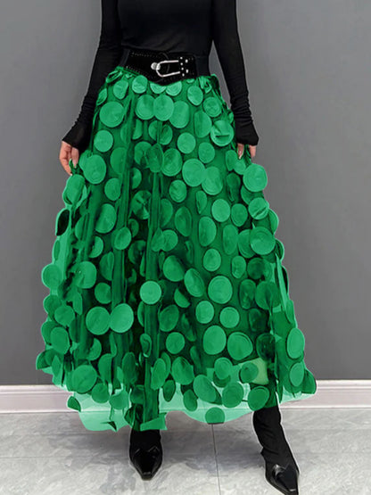 Gonna lunga verde con cerchi decorativi, indossata con cintura nera e stivali a punta. Moda femminile, abbigliamento elegante, tendenze 2023.