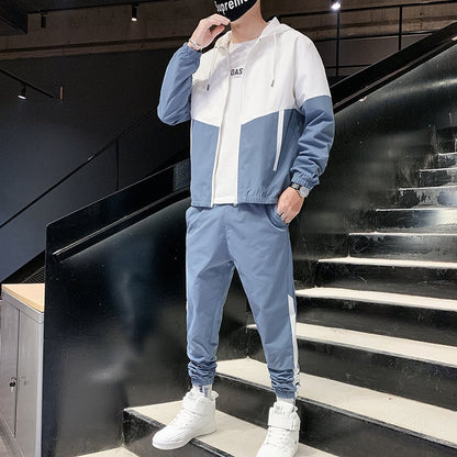 Uomo in tuta sportiva blu e bianca su scala nera, indossa cappello e scarpe bianche. Moda streetwear, abbigliamento casual maschile.