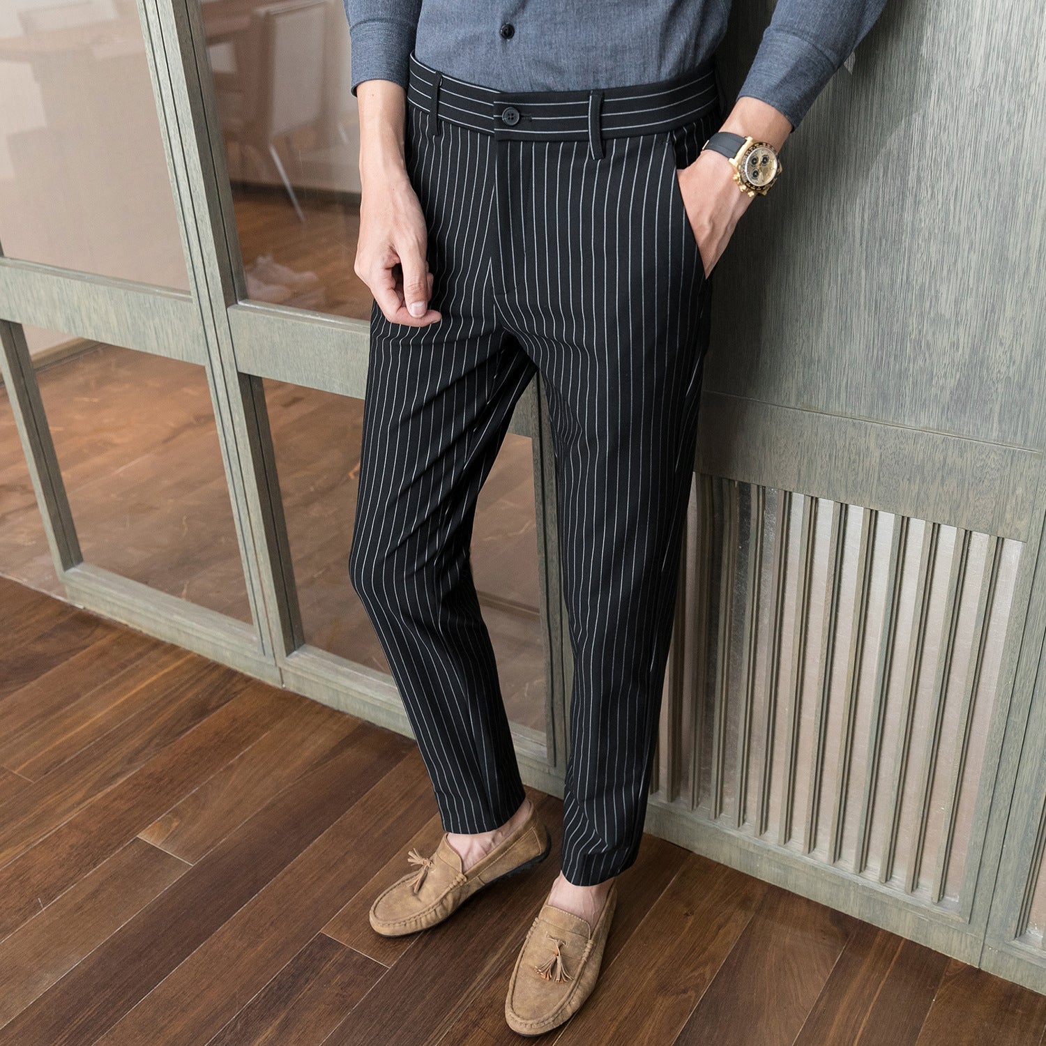 Uomo con pantaloni a righe nere e scarpe mocassino beige su pavimento in legno. Stile elegante, moda maschile, abbigliamento formale.