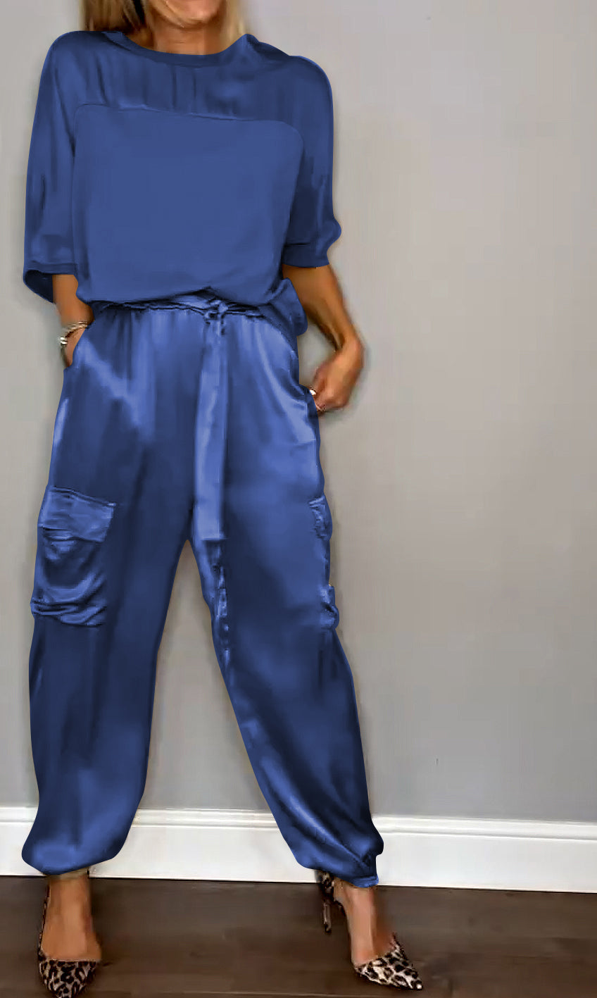 Donna in tuta blu satinata con tasche, maniche corte, scarpe leopardate. Moda elegante, abbigliamento casual chic, stile contemporaneo.