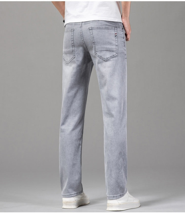 Jeans uomo grigi, taglio dritto, indossati con scarpe bianche e maglietta bianca. Moda casual, abbigliamento maschile, stile moderno.