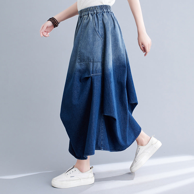 Gonna lunga in denim blu sfumato, design asimmetrico, tasca frontale, abbinata a scarpe bianche casual. Moda donna, abbigliamento trendy.
